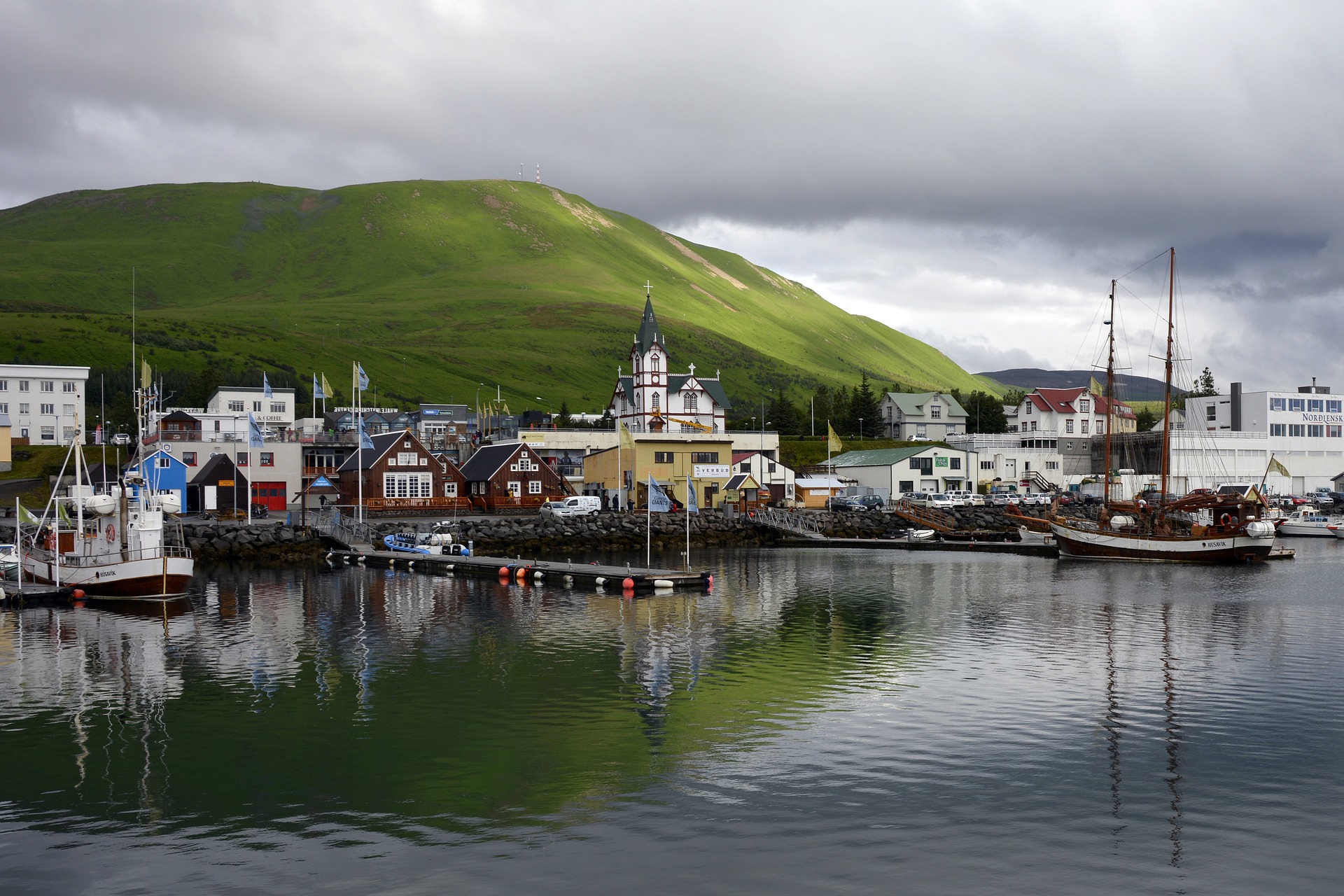 Husavik harbor and town with boats, and mountains on the background