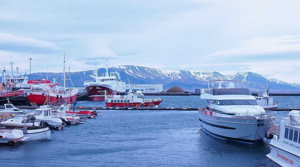 Reykjavik harbor, water body, boats, docks and mountains on the background