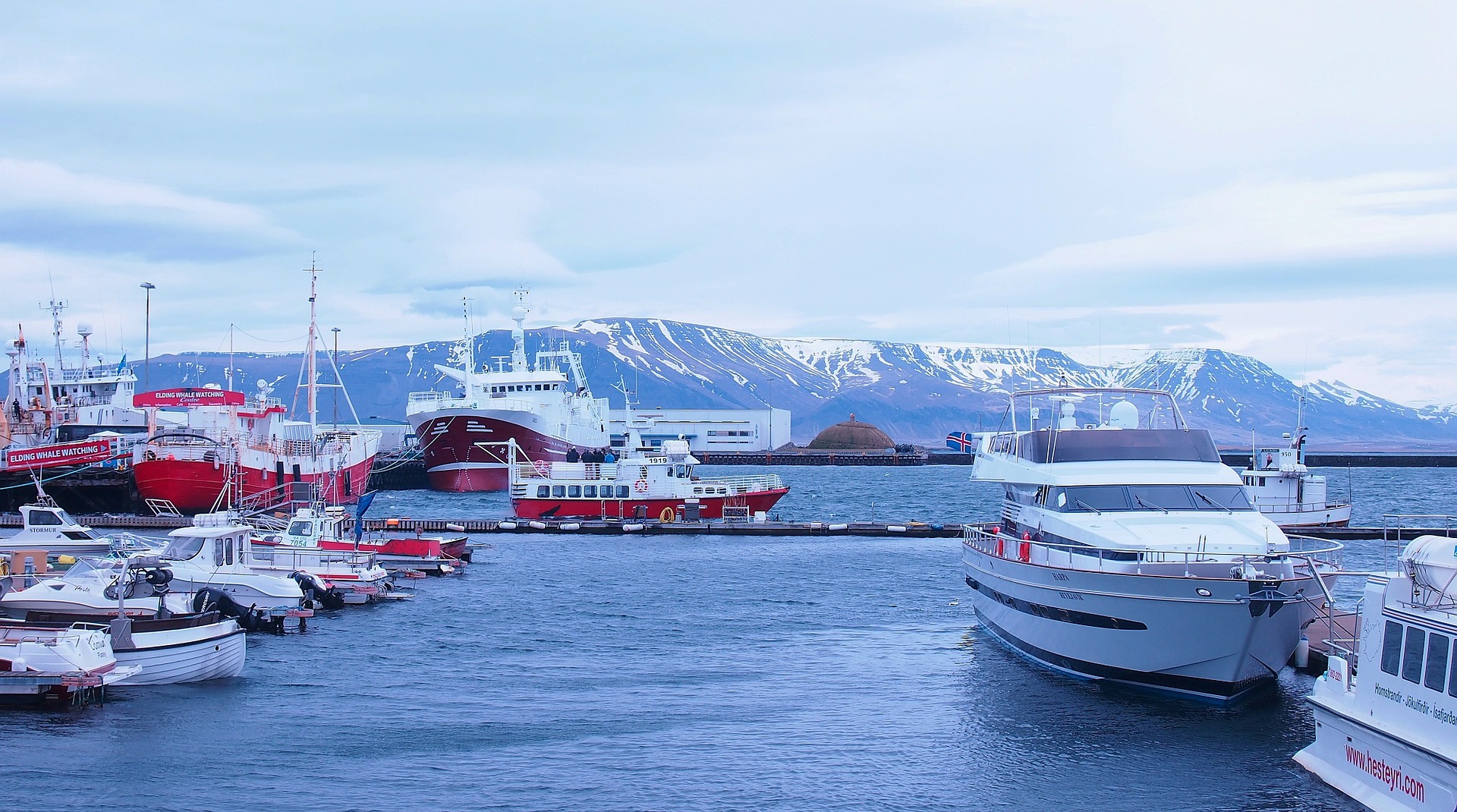 Reykjavik old harbor, boats, water and mountains on the background