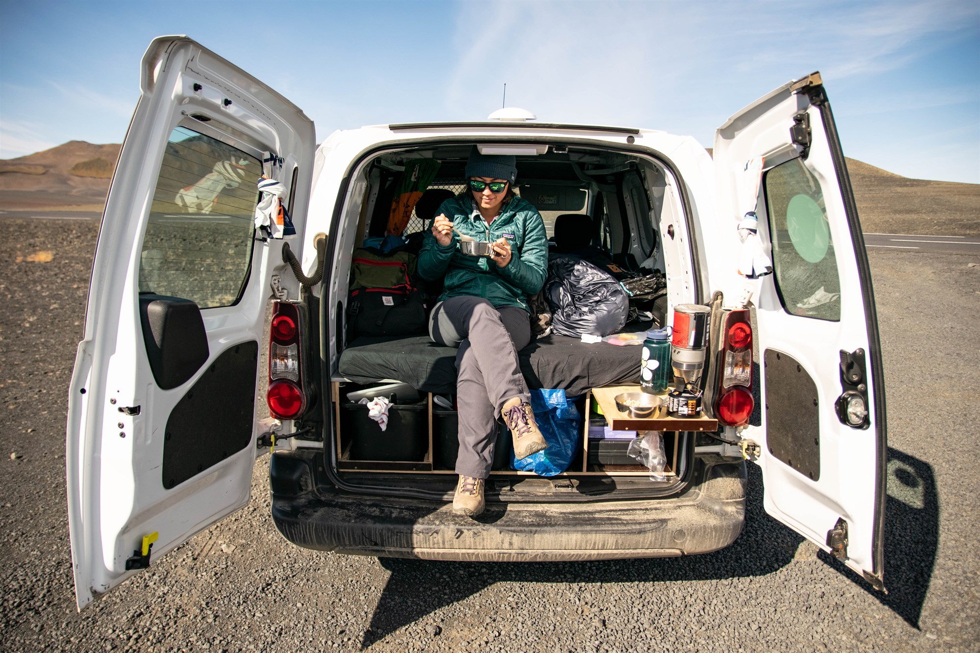 Le vrai mode camping car en Islande Voyageur installé dans l’arrière d’un van au milieu des paysages islandais, version authentique du road trip où chaque arrêt devient un salon improvisé avec vue volcanique.