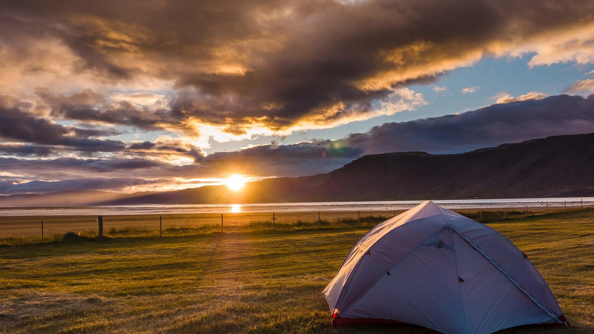 Tente installée dans un camping en Islande au coucher du soleil avec vue sur la mer et les montagnes expérience de camping nature en Islande