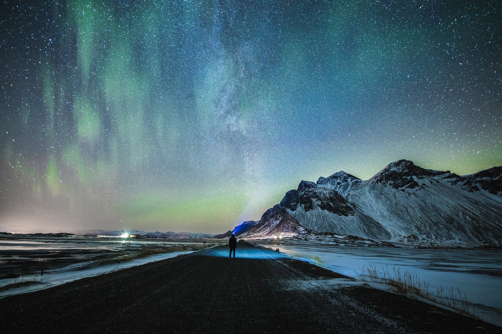 Northern lights in Iceland, man with a light an icelandic road