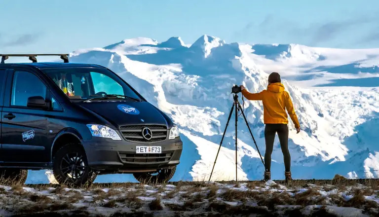 Van aménagé stationné face à un glacier en Islande, expérience immersive en road trip dans des paysages uniques.